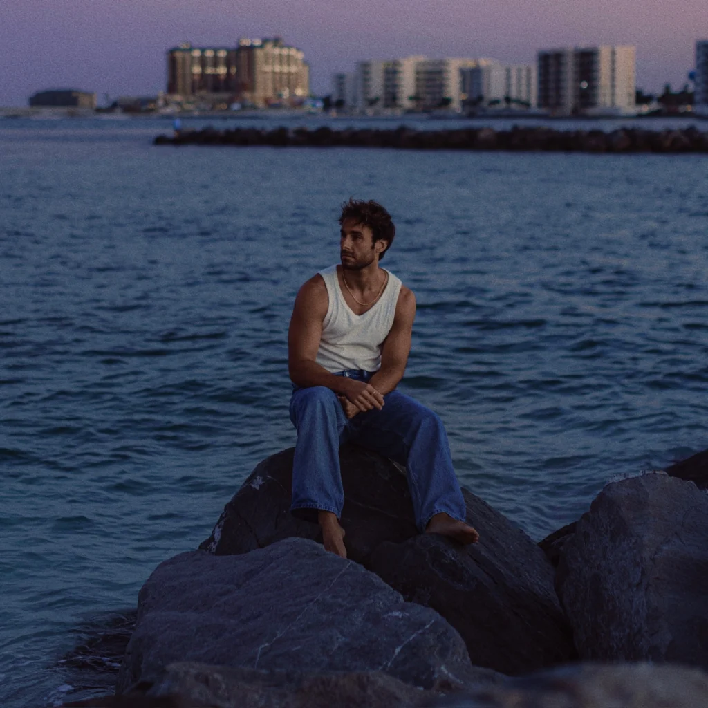 Jesse Foy, Filmmaker, sitting on a rock near water